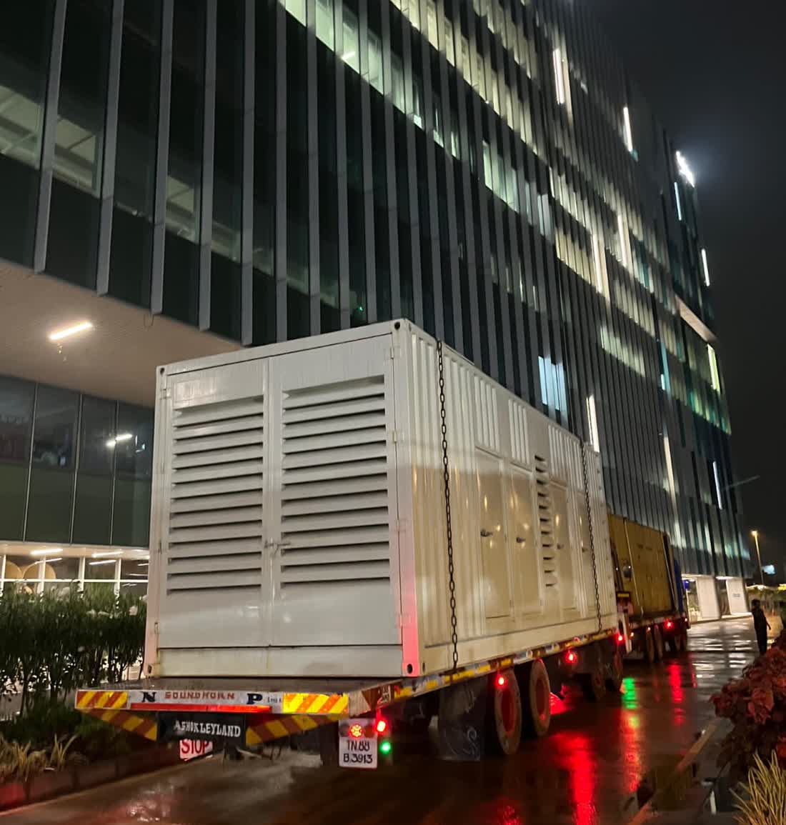 Excel Gentech branded diesel generator truck delivering to a corporate high-rise client site at night