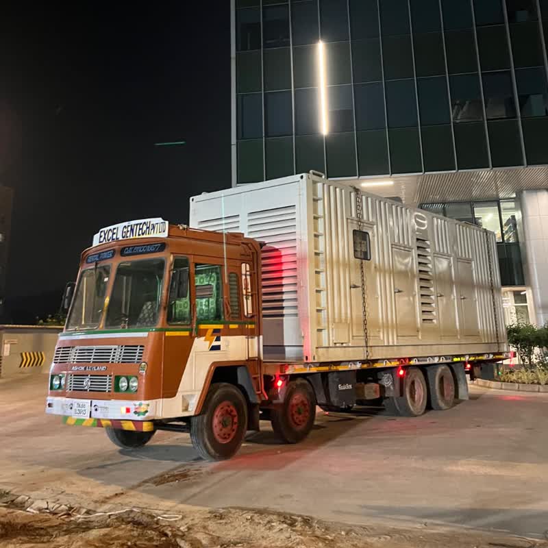 Excel Gentech branded truck delivering a diesel generator to a corporate site at night
